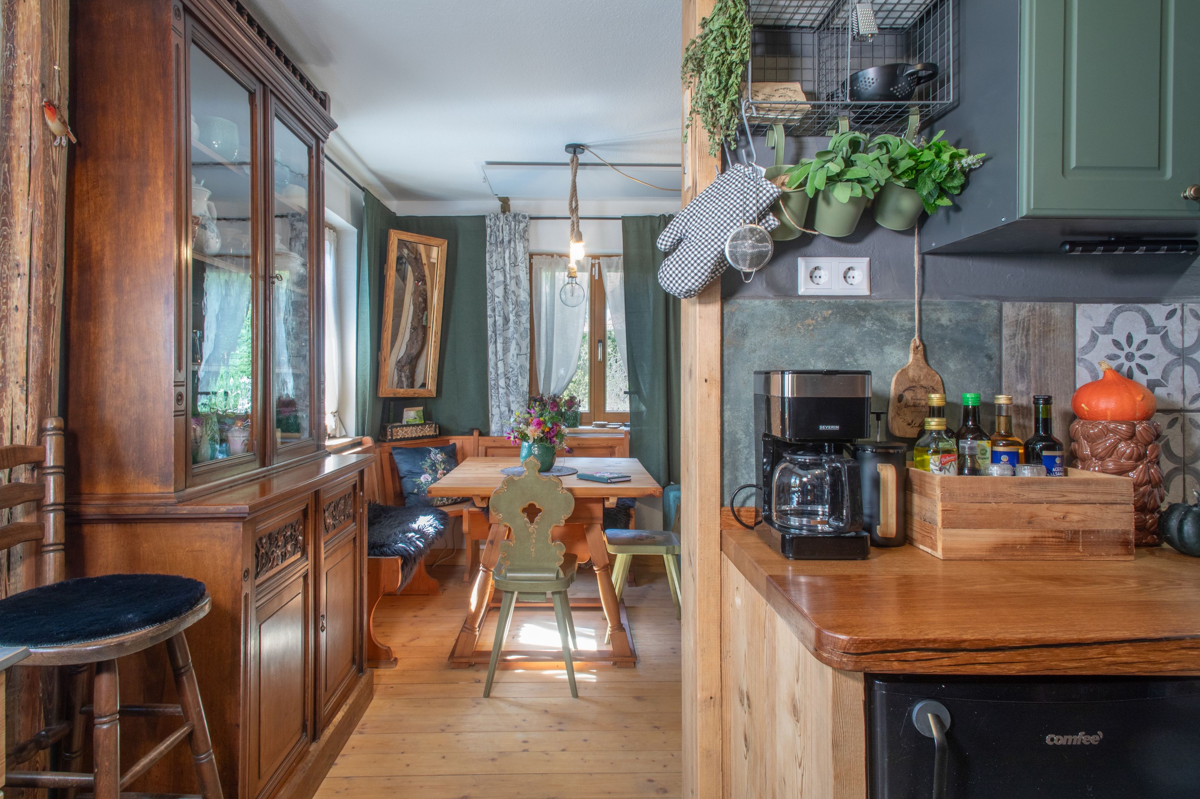 A kitchen with wooden cabinets, a coffee machine, and hanging plants.