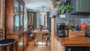 A kitchen with wooden cabinets, a coffee machine, and hanging plants.