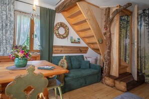Una habitació acollidora amb una escala de fusta, un sofà verd i una taula de dinar amb un ram de flors.