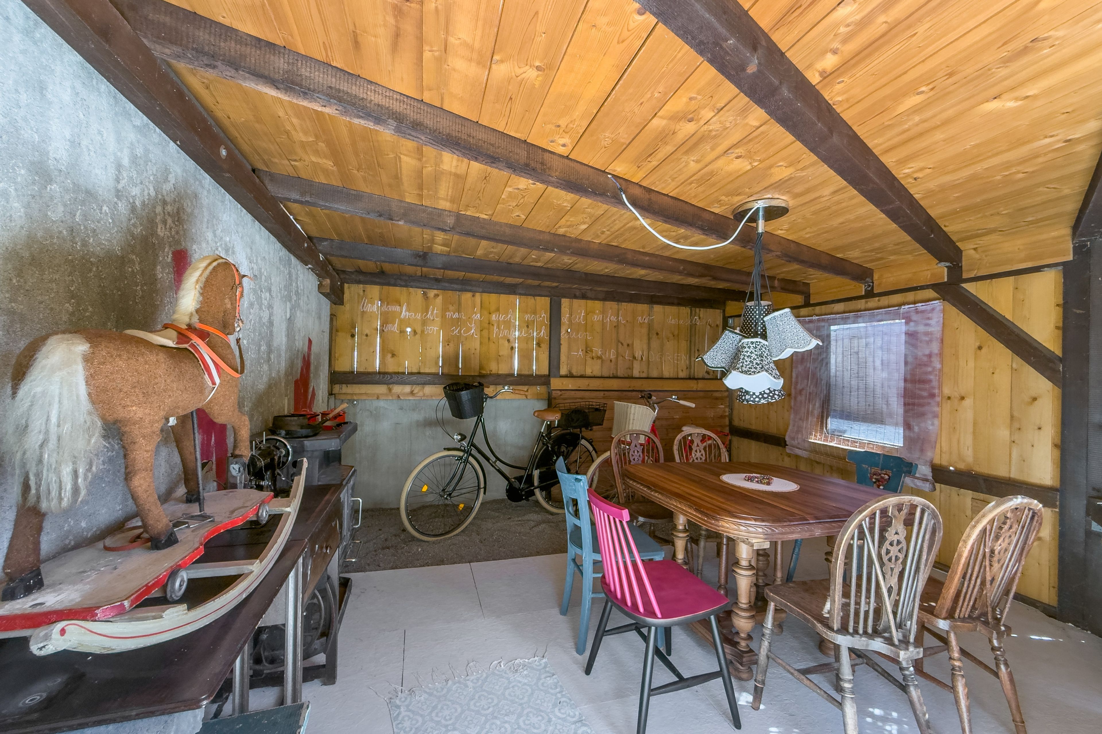 Ein rustikales Holzinterieur mit einem Esstisch, Stühlen, einem Fahrrad und einer Wandleuchte.