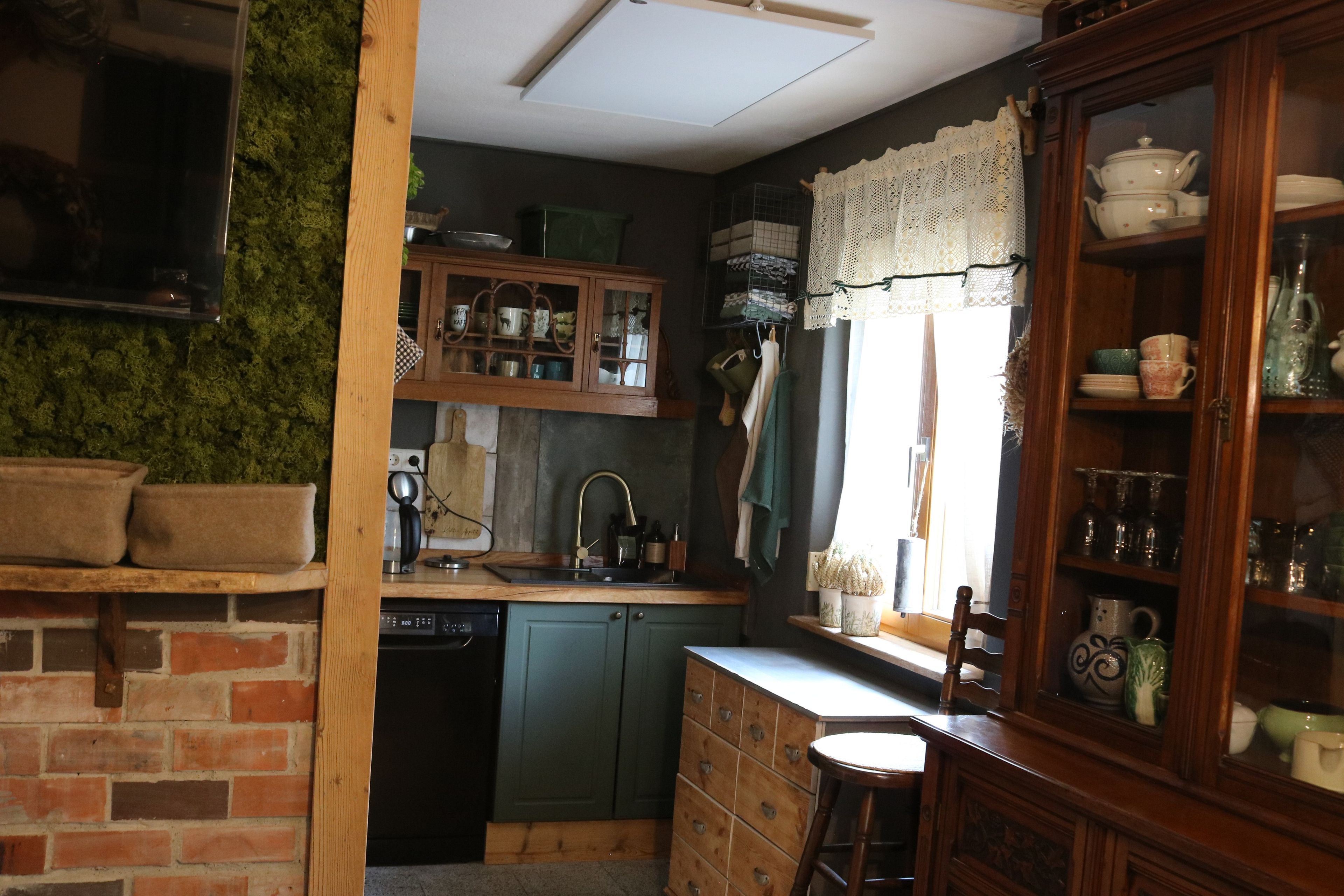 Eine Küche mit Backsteinwand, Holzschränken und einer Wand aus grünem Moos.