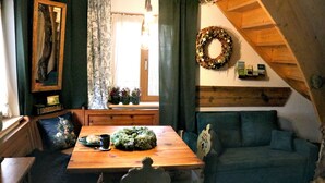 Una habitación acogedora con una mesa de comedor de madera, un sofá verde y techo de madera.