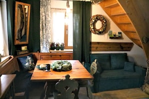 Una habitación acogedora con una mesa de comedor de madera, un sofá verde y techo de madera.