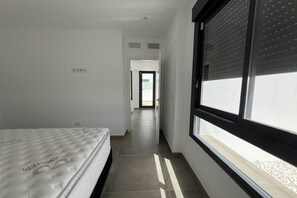 A narrow hallway with a bed on the left and a window on the right.
