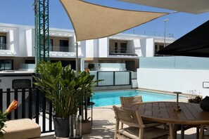 A poolside area with a wooden table and chairs, a potted plant, and a pool. - Casa del Sol – Exclusive Villa, Private Pool & Jacuzzi (Dolores)