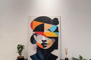 A painting with abstract geometric shapes and a partial view of a room with a plant and a vase. - Arte di Roma Guesthouse (Rome)