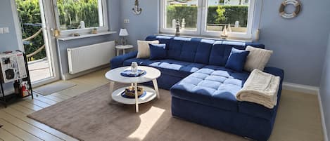 Un salon avec un canapé d’angle bleu, une table basse ronde et un tapis beige.