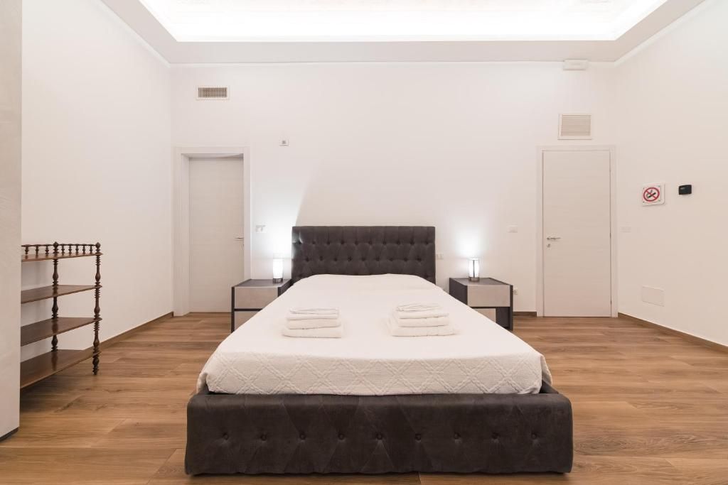 Un dormitorio con cama, mesitas de noche, un armario y una escalera.