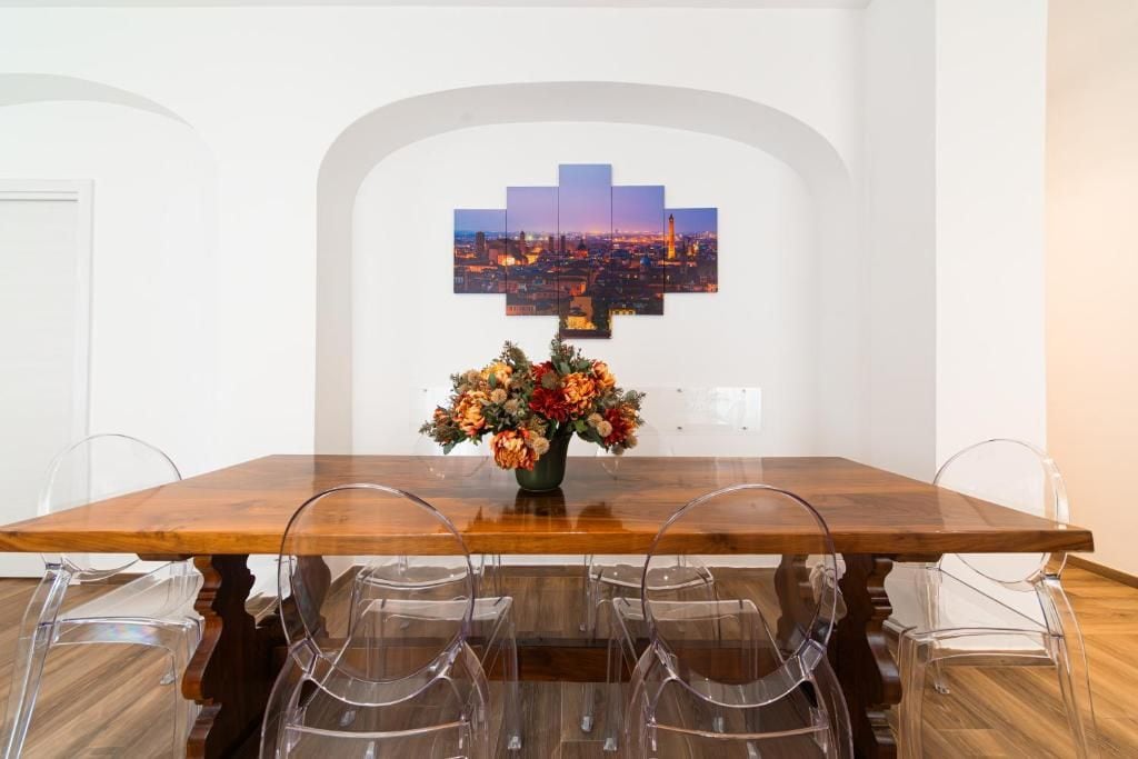 Ein Essbereich mit einem Holztisch, klaren Stühlen, einer floralen Tischdekoration und einem Stadtbild-Kunstwerk an der Wand.