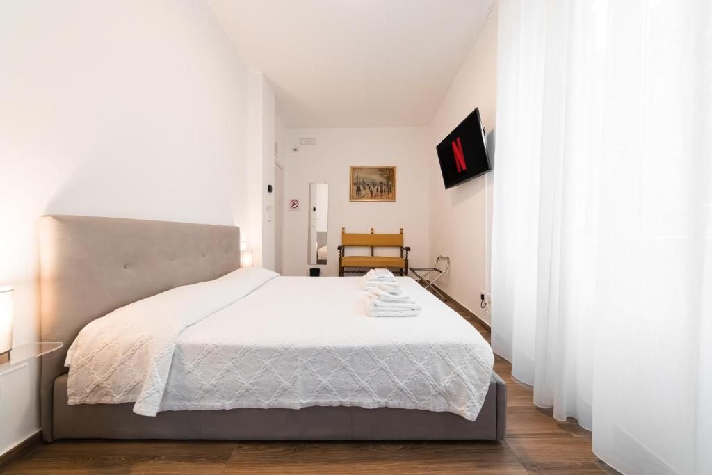 Ein Hotelzimmer mit einem Bett, einem an der Wand befestigten Fernseher und einem Gemälde.