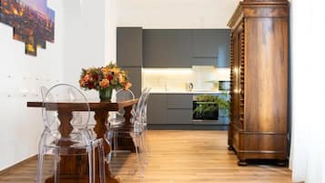 Una cocina moderna con armarios grises, una mesa de comedor de madera con sillas traslúcidas y un mueble grande de madera.