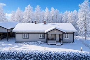 A two-story house with a garage, a covered porch, and a snow-covered landscape. - Aurora Forest House, Sauna By Lapland Host (Rovaniemi)