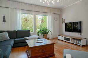 Ein Wohnzimmer mit einer Couch, einem Couchtisch, einem Fernseher und einem Bücherregal.