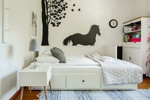 Ein Schlafzimmer mit Bett, Nachttisch, Lampe, Wandbild und einem Kleiderschrank.