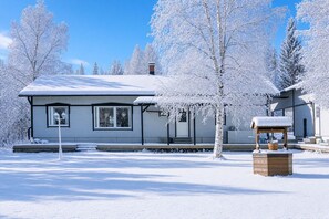 Ein schneebedecktes Haus mit Veranda und einer hölzernen Bank.