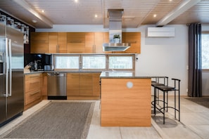 Eine moderne Küche mit Holzschränken, Edelstahlgeräten und einer zentralen Kochinsel mit Hockern.