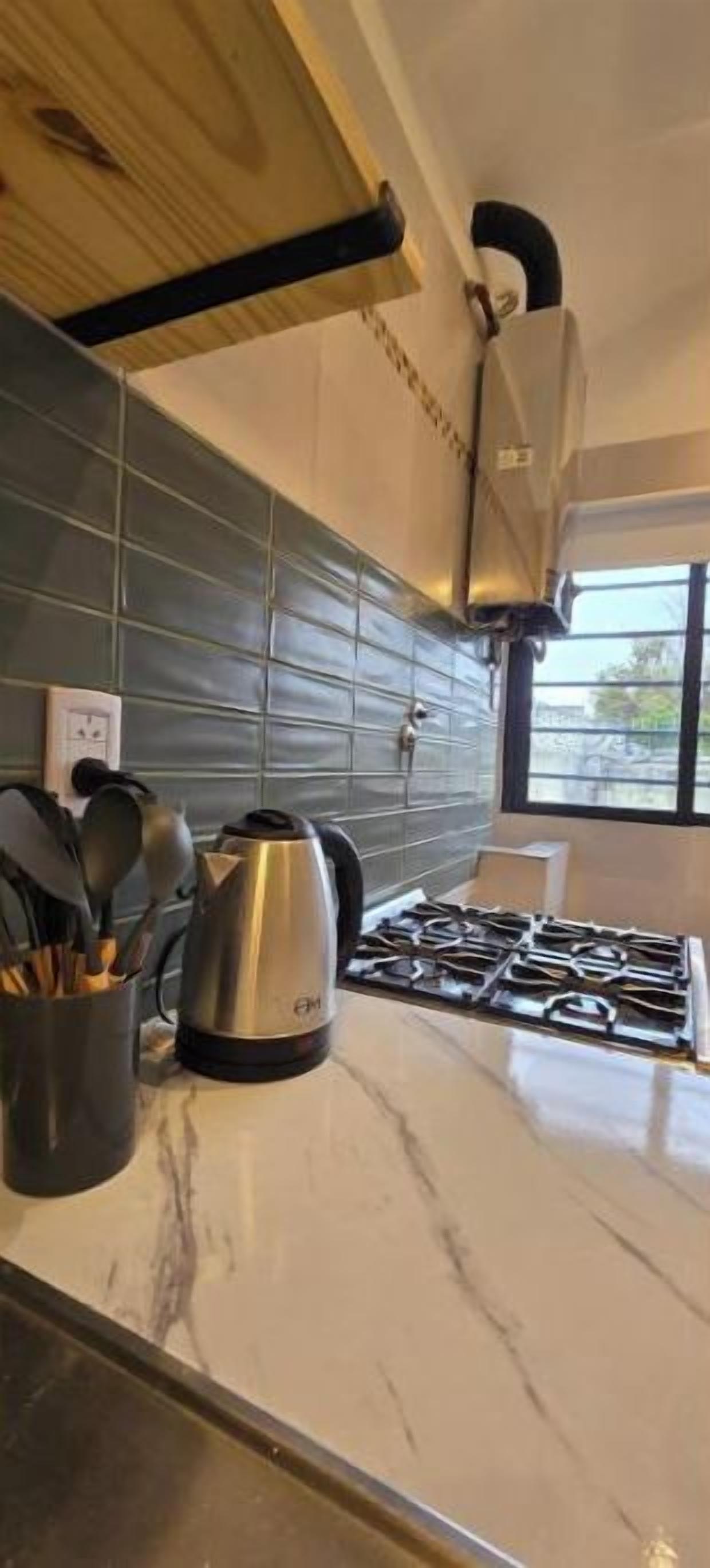 Une cuisine équipée d’une cuisinière à gaz, d’une bouilloire et d’un porte-ustensiles.