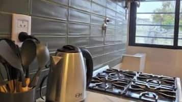 Une cuisine équipée d’une cuisinière à gaz, d’une bouilloire et d’un porte-ustensiles.