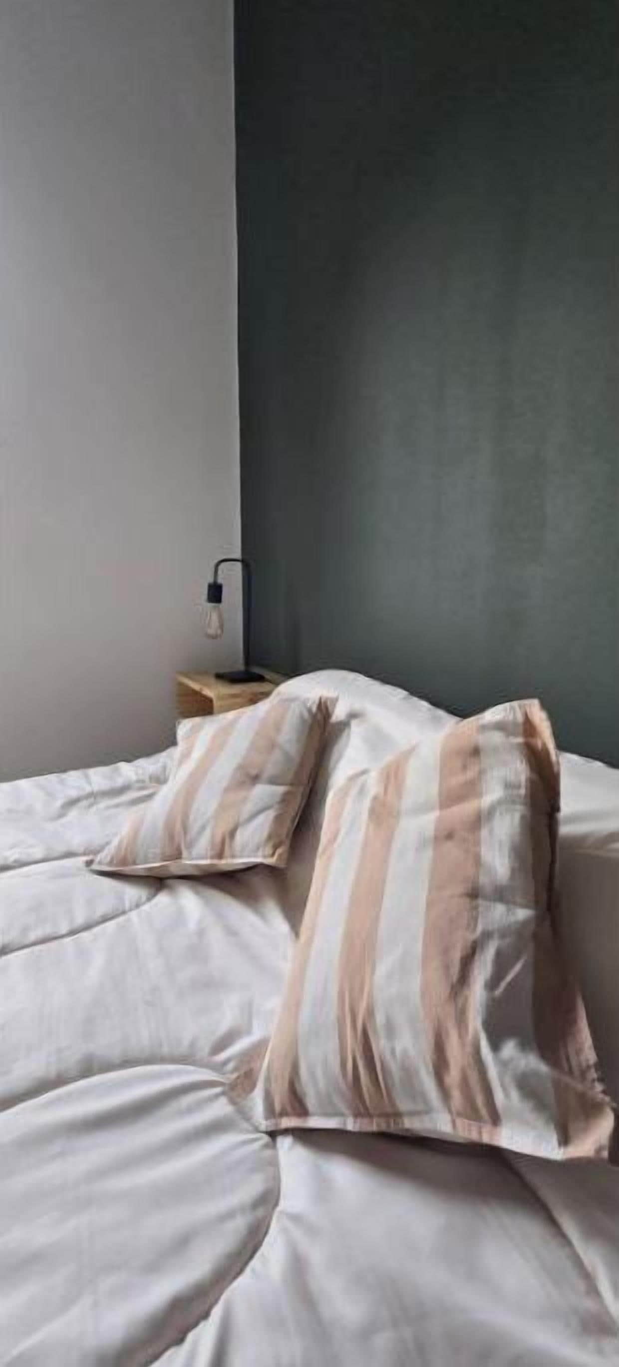 Un lit avec des oreillers à rayures et une lampe de chevet.