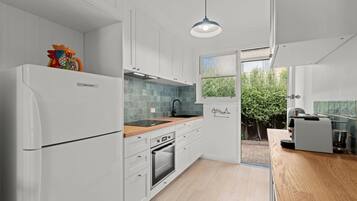 Una cucina moderna con mobili bianchi, un piano di lavoro in legno e un forno integrato.