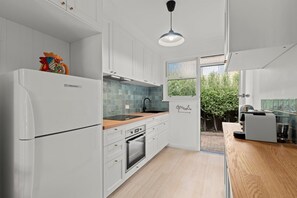 Una cucina moderna con mobili bianchi, un piano di lavoro in legno e un forno integrato.