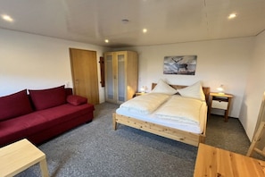 A bedroom with a bed, a red sofa, a wooden wardrobe, and a painting on the wall. - Holiday apartment in Todtnau with barbecue (Todtnau)