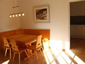 Ein Essbereich mit einem Holztisch und Stühlen, einem Bild an der Wand und einer Küche im Hintergrund.