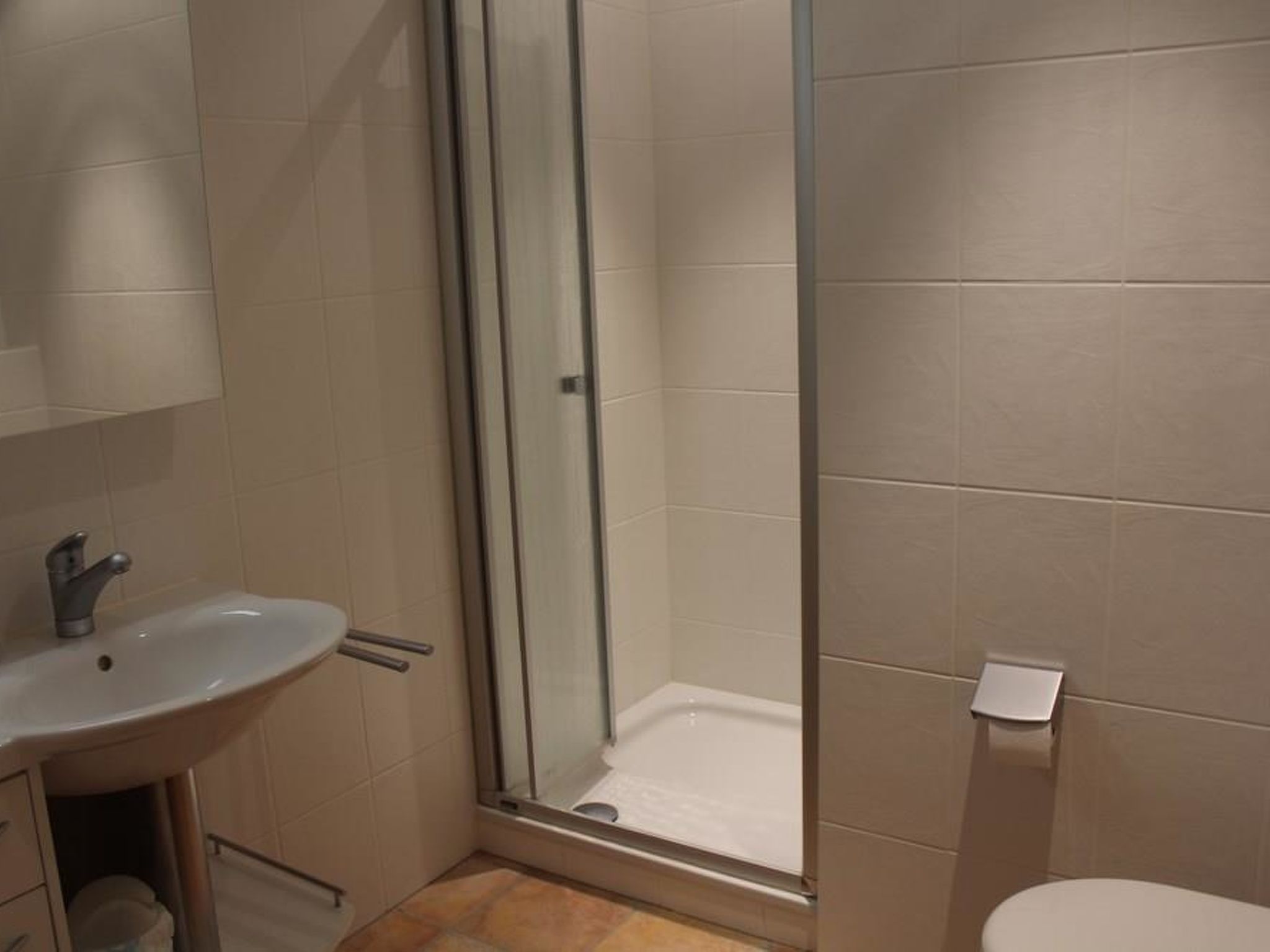 Ein Badezimmer mit einer Duschkabine, einem Waschbecken mit Wasserhahn und einer Toilette.