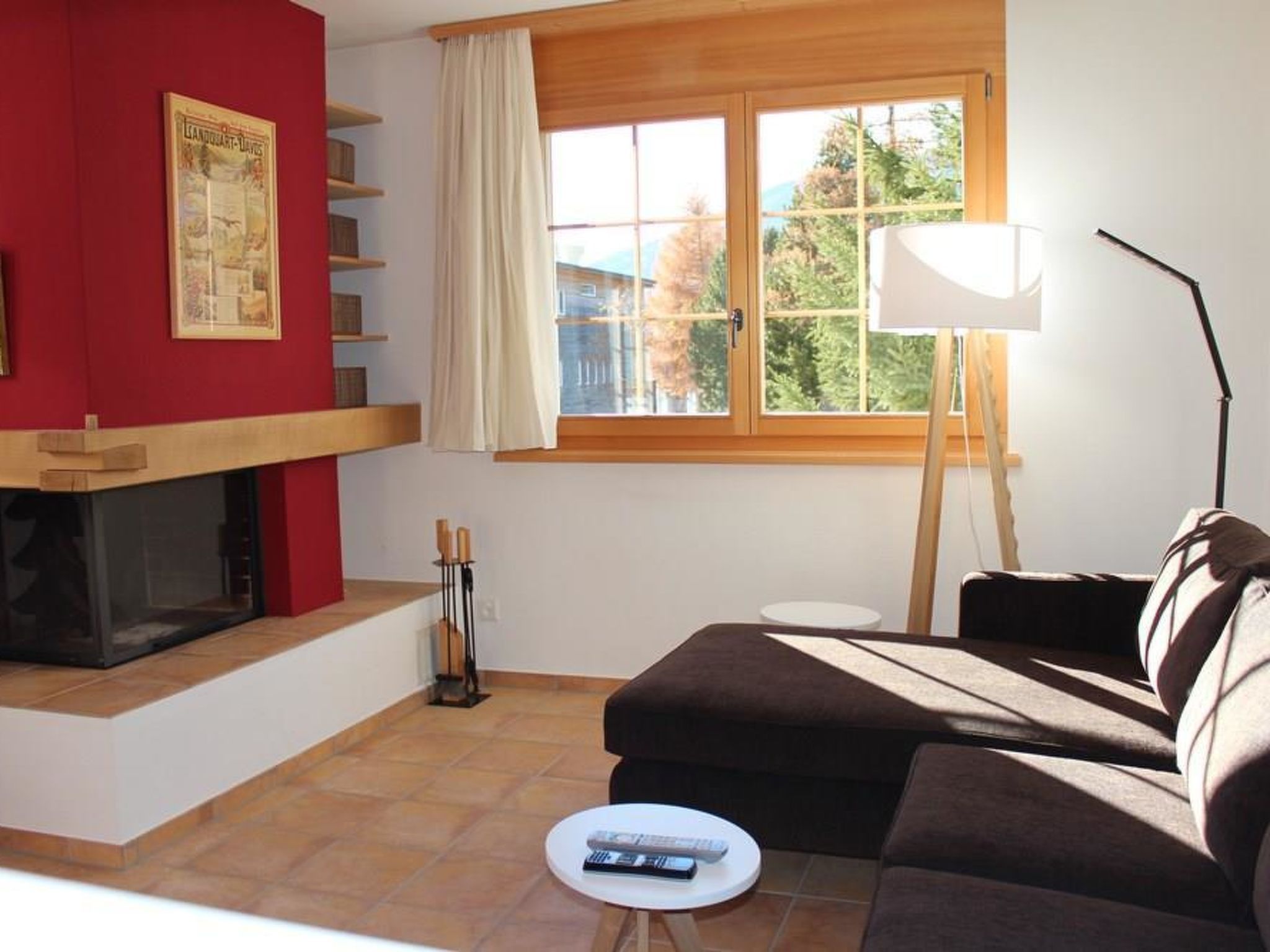 Un salon avec un canapé, une petite table, une lampe, une cheminée et une fenêtre avec des rideaux.