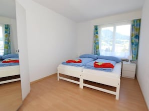 A bedroom with two single beds, a window with curtains, and a wooden floor. - Bündalodge 1028 Appartement/Fewo, Dusche oder Bad, WC 4-Zimmerwohnung by Interhome (Davos)