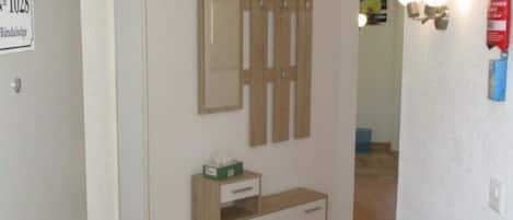 Ein Flur mit einem Holzschrank, einem kleinen Tisch mit Taschentuchbox und einem Schild, das Zimmer Nummer 1028 anzeigt.