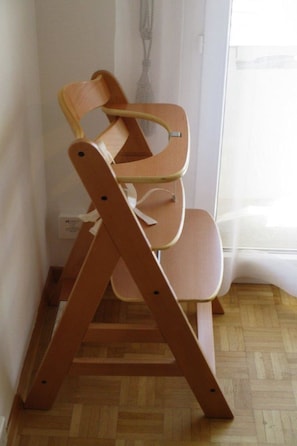 Ein Stuhl aus Holz mit einem besonderen Design, platziert in einem Raum mit Holzboden und weißen Wänden.