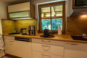 A kitchen with a wooden countertop, a coffee maker, a kettle, and a window with a view of trees. - Holiday home with 1 bedroom (Marktschellenberg bei Berchtesgaden)