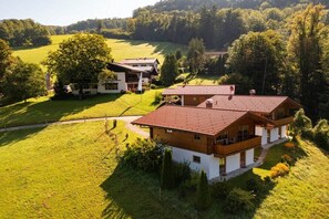 A two-story house with a red-tiled roof, surrounded by green fields and trees. - Holiday home with 1 bedroom (Marktschellenberg bei Berchtesgaden)