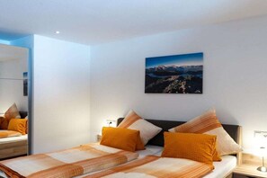 A hotel room with a bed, a nightstand, a lamp, and a wall-mounted picture of a mountain landscape. - Holiday home with 1 bedroom (Marktschellenberg bei Berchtesgaden)