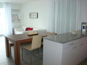 A modern kitchen with a dining area, white cabinetry, and a wooden table. - Mühlestrasse 3B (MAI) Appartement/Fewo, Dusche oder Bad, WC 3½-Zimmerwohnung by Interhome (Davos)