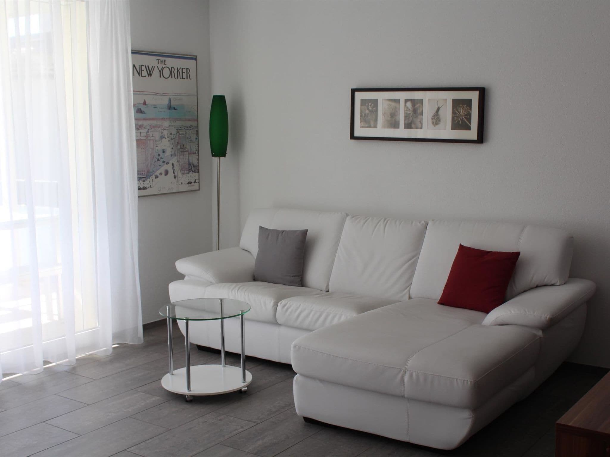 Una sala moderna con un sofá blanco, una mesa de centro de vidrio y un cuadro enmarcado en la pared.
