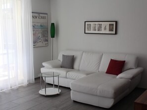 A modern living room with a white sofa, a glass coffee table, and a framed picture on the wall. - Mühlestrasse 3B (MAI) Appartement/Fewo, Dusche oder Bad, WC 3½-Zimmerwohnung by Interhome (Davos)