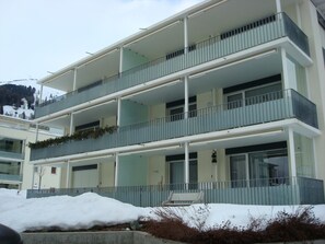 A multi-story building with balconies, a snow-covered ground, and a mountainous backdrop. - Mühlestrasse 3B (MAI) Appartement/Fewo, Dusche oder Bad, WC 3½-Zimmerwohnung by Interhome (Davos)