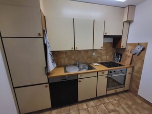 A compact kitchen with a dishwasher, stove, oven, and a small countertop. - Talstrasse 22 App 12 Appartement/Fewo, Dusche oder Bad, WC 2-Zimmerwohnung by Interhome (Davos)