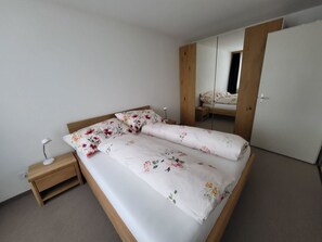 A single bed with floral bedding, a bedside table with a lamp, and a wardrobe with a mirror. - Talstrasse 22 App 12 Appartement/Fewo, Dusche oder Bad, WC 2-Zimmerwohnung by Interhome (Davos)