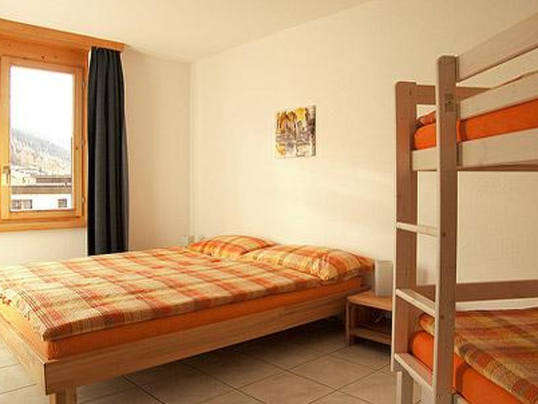 Una cama individual con estructura de madera y una litera a juego al lado derecho.