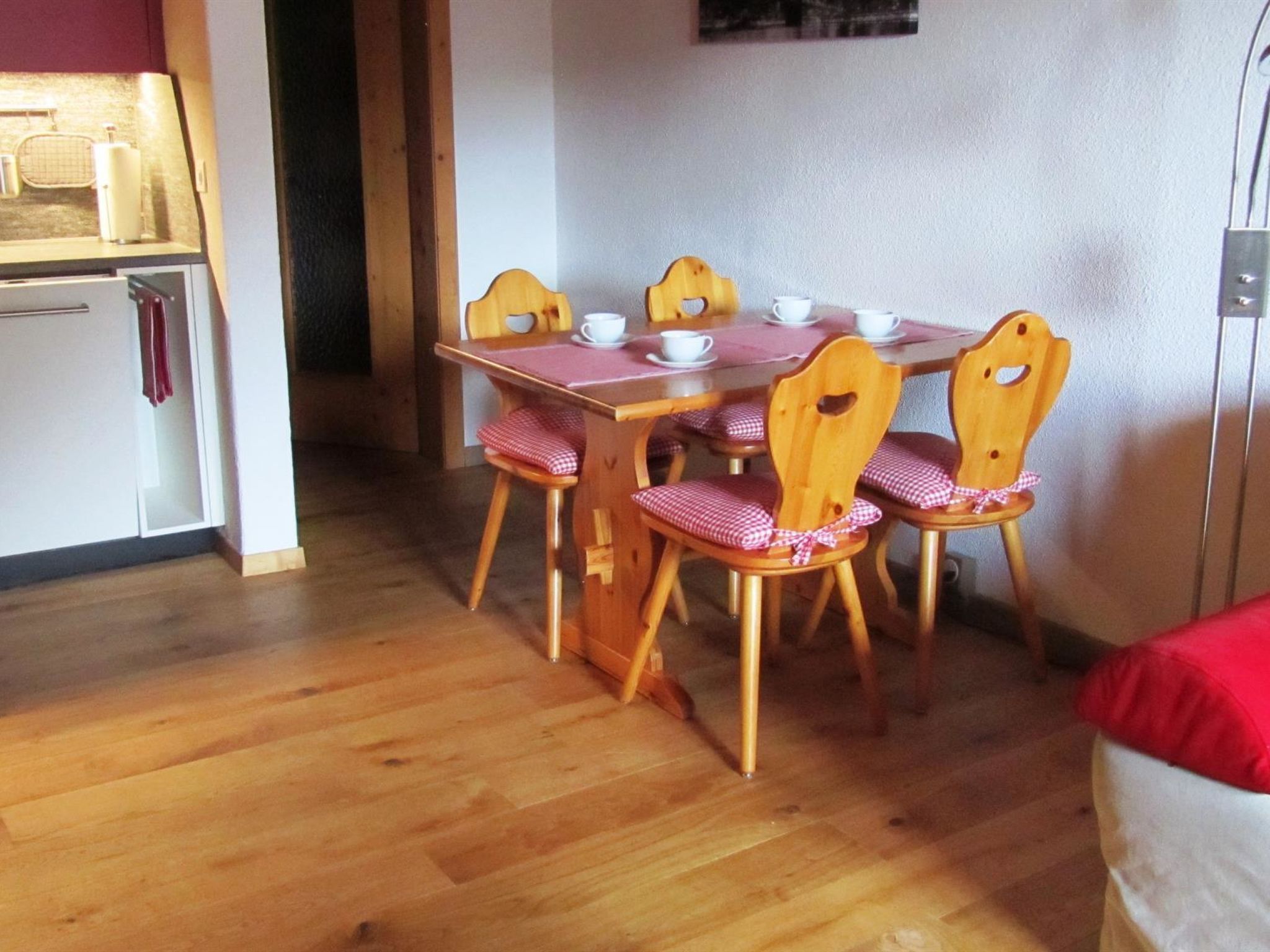 Ruokailutilassa on puinen pöytä ja tuolit, jääkaappi sekä keittiötaso.