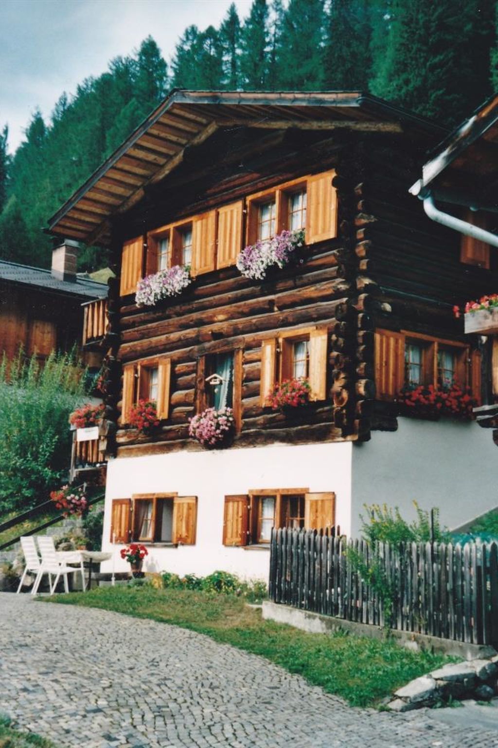 A traditional chalet with a wooden facade, multiple windows with shutters, and flower boxes on the balconies.