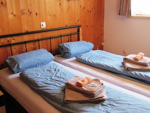 A room with three single beds, each with a blue patterned bedspread and pillows. There are folded towels on the beds. - Im Gadä Appartement/Fewo, Dusche oder Bad, WC 3-Zimmerwohnung by Interhome (Davos)