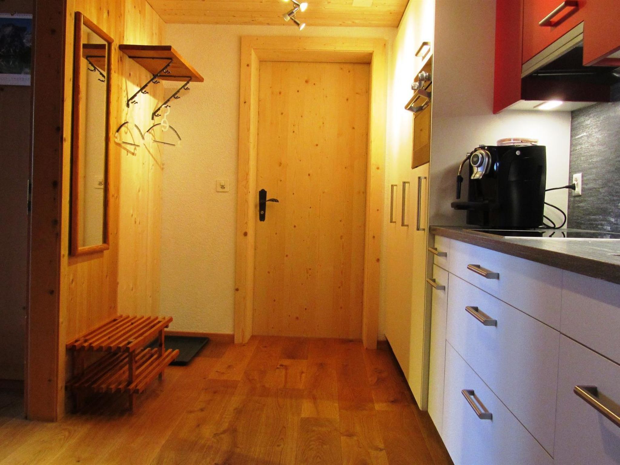 A compact kitchen with wooden cabinets, a coffee machine, and a bench.