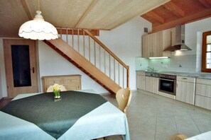 Ein Essbereich mit einem Tisch für zwei Personen, eine Holztreppe und eine Küche mit modernen Geräten.