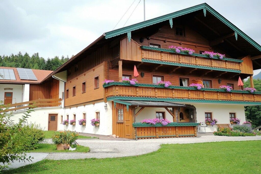 A multi-story wooden building with balconies, a covered entrance, and flower boxes.
