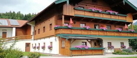 Un immeuble en bois à plusieurs étages, doté de balcons, d’une entrée couverte et de jardinières.