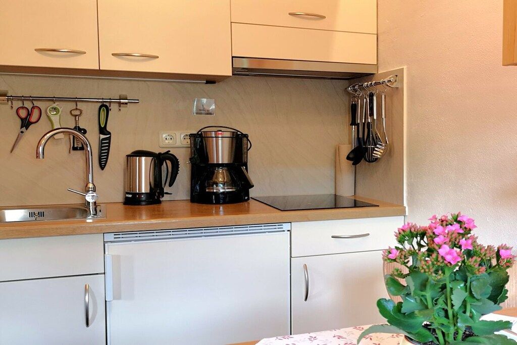 A kitchen with a coffee maker, utensils, and a sink.
